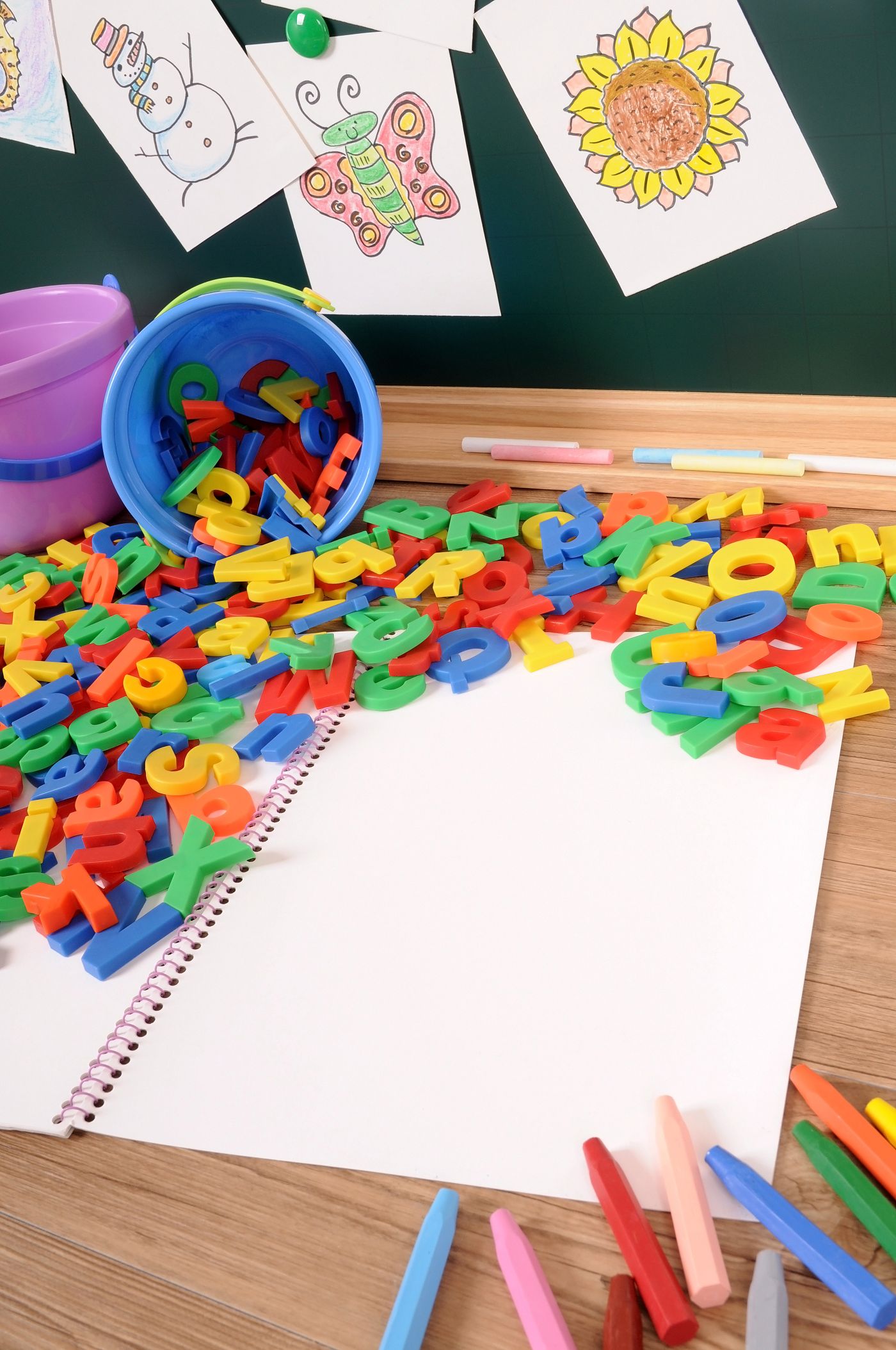 Mesa con letras de colores, cuaderno y material escolar: lenguaje y creatividad en la primera infancia